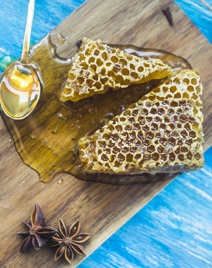 Raw honeycomb and honey on a wooden board
